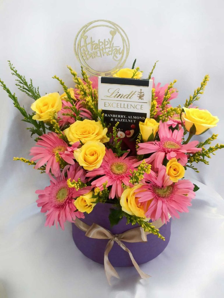 Birthday basket of yellow and pink flowers with a Lindtt bar