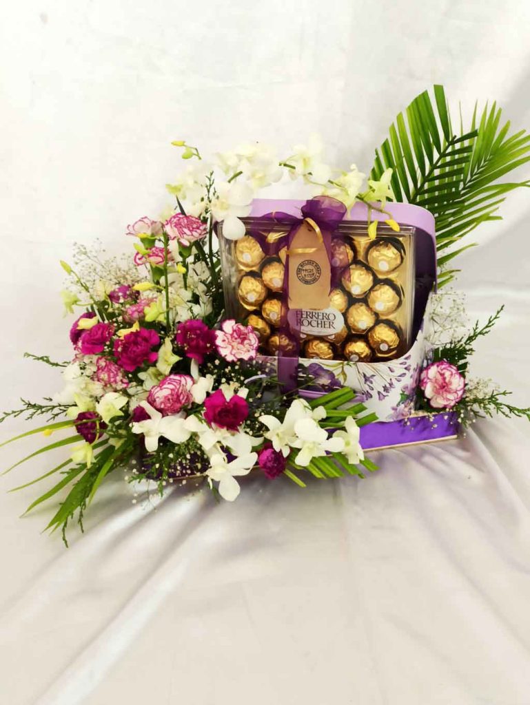 A Ferrero Rocher box with violet and white flower arrangement